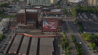 AX80_030 - 4.8K aerial stock footage of an American flag mural on a warehouse building in Philadelphia, Pennsylvania, Sunset