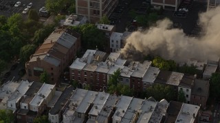 AX80_041 - 4.8K aerial stock footage of a reverse view of a residential fire near Downtown Philadelphia, Pennsylvania, Sunset