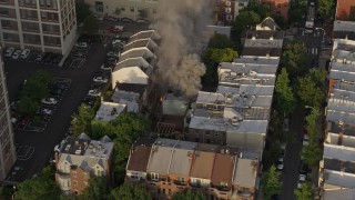 AX80_043 - 4.8K aerial stock footage tracking a residential fire near Downtown Philadelphia, Pennsylvania, Sunset