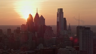 AX80_130E - 4.8K aerial stock footage of the setting sun behind the Downtown Philadelphia skyline, Pennsylvania, Sunset