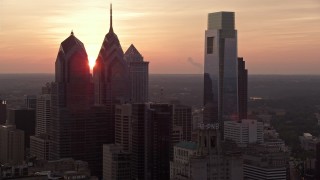 AX80_146E - 4.8K aerial stock footage of tall Downtown Philadelphia skyscrapers and City Hall, reveal setting sun, Pennsylvania, Sunset