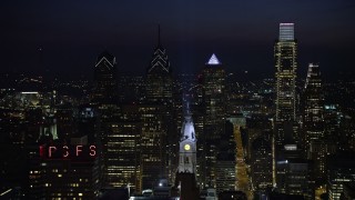 AX81_042 - 4.8K aerial stock footage flying by City Hall clock tower with tall Downtown Philadelphia skyscrapers behind it, Pennsylvania, Night