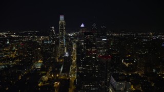 AX81_053E - 4.8K aerial stock footage following John F Kennedy Boulevard to approach Downtown Philadelphia skyscrapers, reveal city hall, Pennsylvania, Night