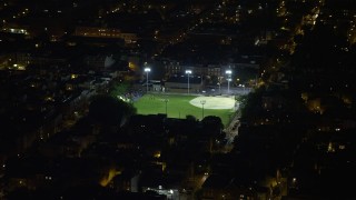 AX81_060 - 4.8K aerial stock footage of baseball field in an urban neighborhood in South Philadelphia, Pennsylvania, Night