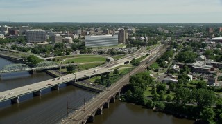 AX82_067E - 4.8K stock footage aerial video approach and orbit bridges spanning the Delaware River, reveal commuter train and courthouse, Trenton, New Jersey