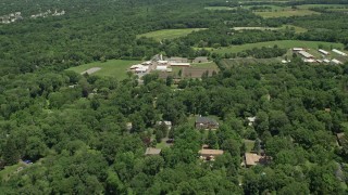 AX83_036E - 4.8K aerial stock footage fly over rural homes to approach a farm, red barns, and fields in Princeton, New Jersey