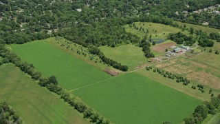 AX83_044 - 4.8K aerial stock footage flying over farm fields and small town neighborhood in Somerset, New Jersey