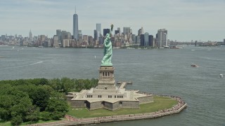 AX83_194E - 4.8K stock footage aerial video orbiting Statue of Liberty and reveal Lower Manhattan skyline, New York City