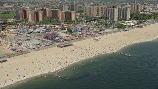 AX83_220E - 4.8K aerial stock footage flying by Luna Park, Riegelmann Boardwalk, and Coney Island Beach sunbathers, Brooklyn, New York City