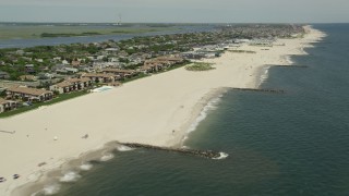 AX83_235E - 4.8K aerial stock footage passing Atlantic Beach apartment complex and beach goers, Long Island, New York