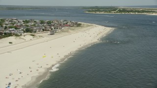 AX83_248 - 4.8K aerial stock footage of a small group of people on the beach near beachfront homes, Point Lookout, New York