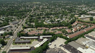 AX83_265E - 4.8K aerial stock footage flying by suburban neighborhoods to reveal warehouses, Republic Airport in Farmingdale, New York