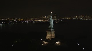 AX85_004 - 4K aerial stock footage of flying by Statue of Liberty, New York, New York, night