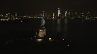 AX85_010 - 4K aerial stock footage of the Statue of Liberty, Lower Manhattan skyline, New York, New York, night