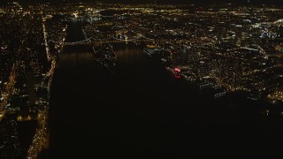 AX85_060 - 4K aerial stock footage Tilt up from East River, revealing Queensboro Bridge, New York, New York, night