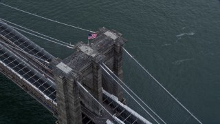 AX86_024 - 4K aerial stock footage of orbiting the American flag atop the Brooklyn Bridge, New York City