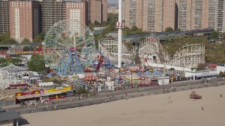 AX88_049 - 4K aerial stock footage of flying away from a Ferris wheel and rollercoasters at Luna Park, Coney Island, Brooklyn, New York