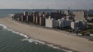 AX88_063 - 4K aerial stock footage of passing by Coney Island Beach and apartment buildings, Brooklyn, New York