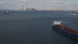 AX88_089 - 4K aerial stock footage tilt from water to reveal oil tanker sailing New York Harbor and Lower Manhattan skyline, New York, New York