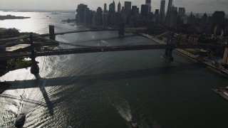 AX88_124 - 4K aerial stock footage tilt from East River, reveal Brooklyn Bridge, Manhattan Bridge, and Lower Manhattan skyscrapers, New York
