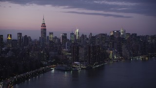 AX89_114 - 4K aerial stock footage Flying by Midtown Manhattan, seen from East River, New York, New York, twilight