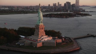 AX90_016 - 4K aerial stock footage Flying by Statue of Liberty, revealing Lower Manhattan, New York, sunrise