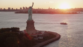 AX90_018 - 4K aerial stock footage Flying by Statue of Liberty, Brooklyn in the distance, New York, New York, sunrise
