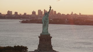 AX90_020 - 4K aerial stock footage Flying by Statue of Liberty, revealing Lower Manhattan, New York, sunrise