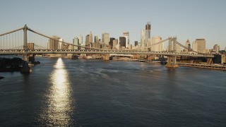 AX90_100 - 4K stock footage aerial video of Manhattan Bridge, Lower Manhattan, reveal Brooklyn Bridge, New York, sunrise
