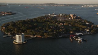 AX90_107 - 4K aerial stock footage Approaching Governors Island, New York Harbor, New York, New York, sunrise