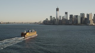 AX90_129 - 4K aerial stock footage Flying by Staten Island Ferry, approaching Lower Manhattan, New York, sunrise