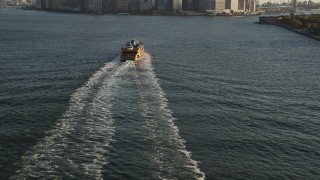 AX90_130 - 4K aerial stock footage Flying by Staten Island Ferry, tilt up to Lower Manhattan, New York, sunrise