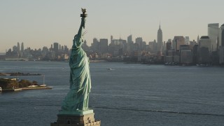 AX90_143 - 4K aerial stock footage of Statue of Liberty, revealing Freedom Tower, Lower Manhattan, New York, sunrise