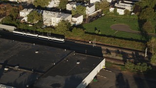 AX90_163 - 4K aerial stock footage Tracking a commuter train passing through, Jersey City, New Jersey, sunrise