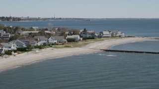 AX91_116 - 4K aerial stock footage of flying by a beach, breakwaters, and beachfront homes in Fairfield, Connecticut