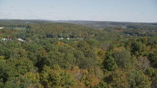 AX91_148 - 4K aerial stock footage of flying over forest, revealing town in autumn, East Haven, Connecticut