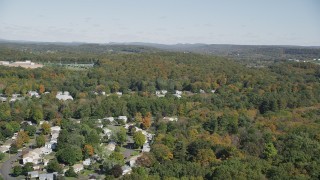 AX91_149 - 4K aerial stock footage fly over forest, pan to suburban neighborhood in autumn, East Haven, Connecticut