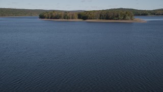 AX91_158 - 4K aerial stock footage tilt from water, revealing small island in autumn, Lake Gallard, Connecticut