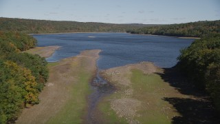 AX91_160 - 4K aerial stock footage of approaching the shore surrounded by fall foliage, Lake Gallard, Connecticut