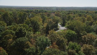 AX91_170 - 4K aerial stock footage of flying over lush forest, revealing homes in autumn, Guilford, Connecticut