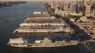 AX93_008 - 4K aerial stock footage Approaching the USS Intrepid, tilting down, New York, New York, sunset