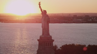AX93_108 - 4K aerial stock footage Flying by the Statue of Liberty, New York Harbor, New York, New York, sunset