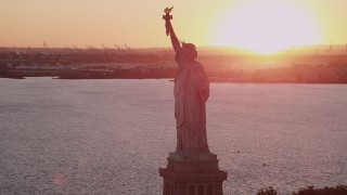 AX93_110 - 4K aerial stock footage Flying by the Statue of Liberty, New York Harbor, New York, New York, sunset