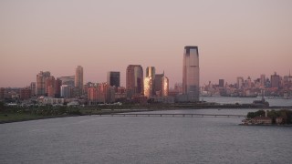 AX93_117 - 4K aerial stock footage Flying by Goldman Sachs Tower, Downtown skyline, Jersey City, New Jersey, sunset