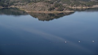AXSF01_019 - 5K aerial stock footage of flying over Casitas Dam, tilt up to reveal hills on the shore of Lake Casitas, California