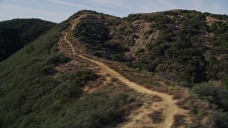 AXSF01_024 - 5K aerial stock footage of flying by dirt road on a mountain ridge, Santa Ynez Mountains, California