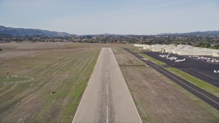 AXSF01_051 - 5K aerial stock footage tilt from vineyard to reveal runway, approach for landing, Santa Ynez Airport, California