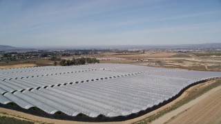 AXSF02_001 - 5K aerial stock footage of flying over farm fields, approaching greenhouses, Santa Maria, California
