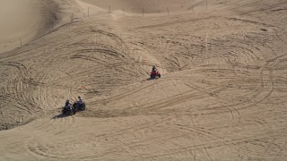 AXSF02_024 - 5K aerial stock footage of orbiting ATV riders on coastal sand dunes, Pismo Dunes, California