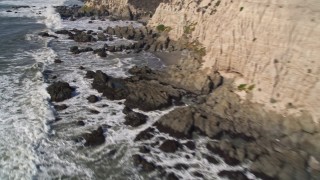 AXSF02_050 - 5K aerial stock footage of tilt from cliffs to waves rolling into rock formations, Avila Beach, California